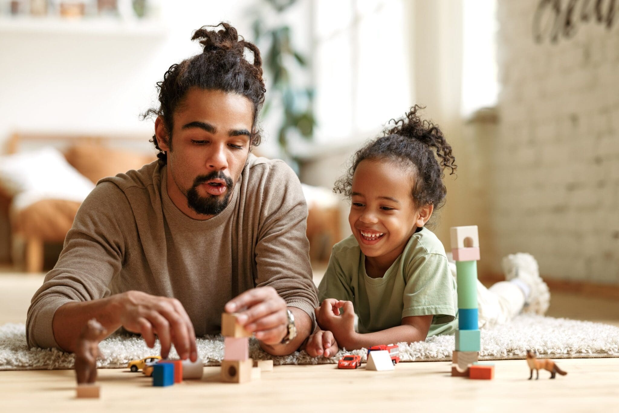 attachment-65a6eb18016630354d77adb4 Father and child playing with building blocks.