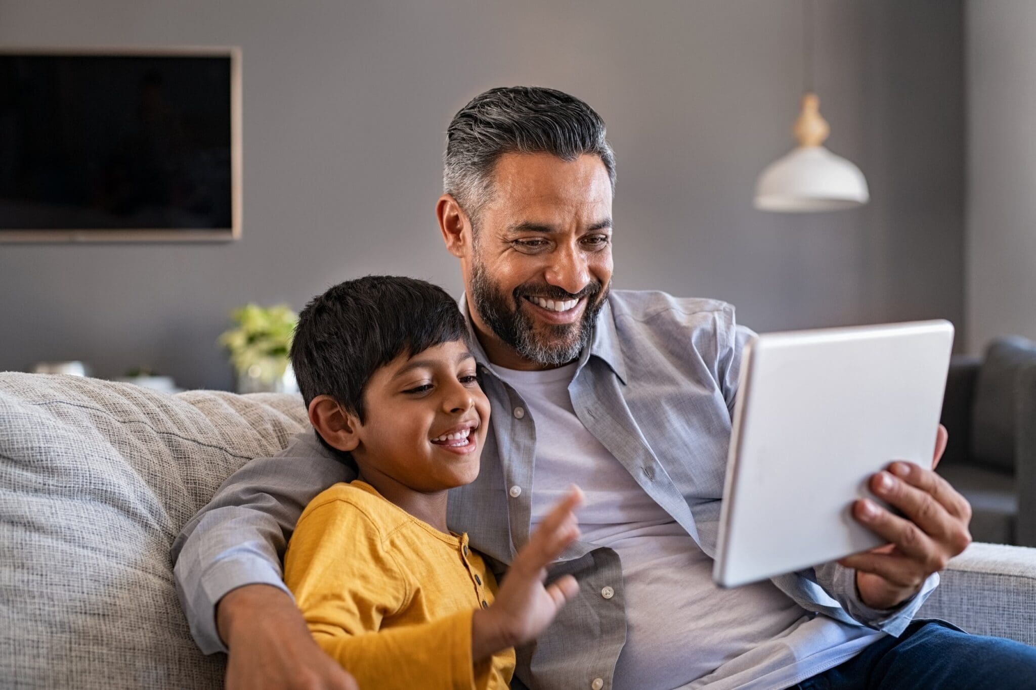 attachment-662b0ff0f1dd8e71c3ea3742 Father and son smiling at tablet screen.