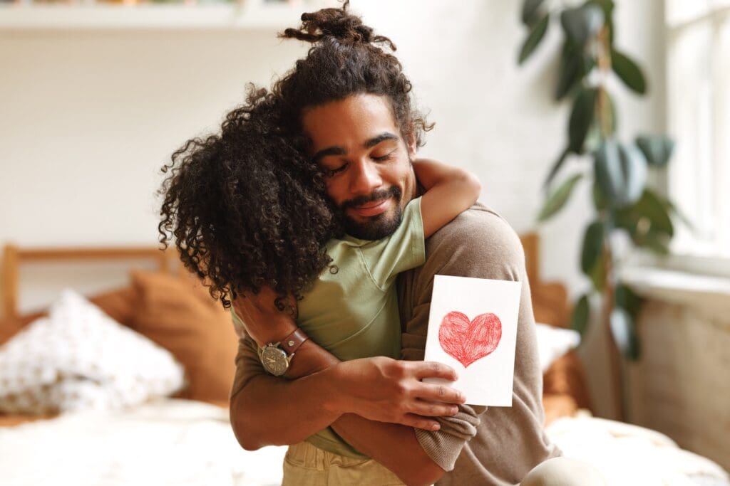 Father and child hugging with heart card, Father's Day.