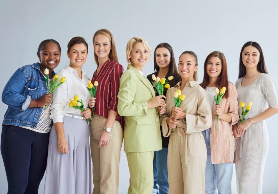 Group portrait of smiling diverse women standing with tulips, celebrating International Women Day. Group of women, posing together for Women's Day.