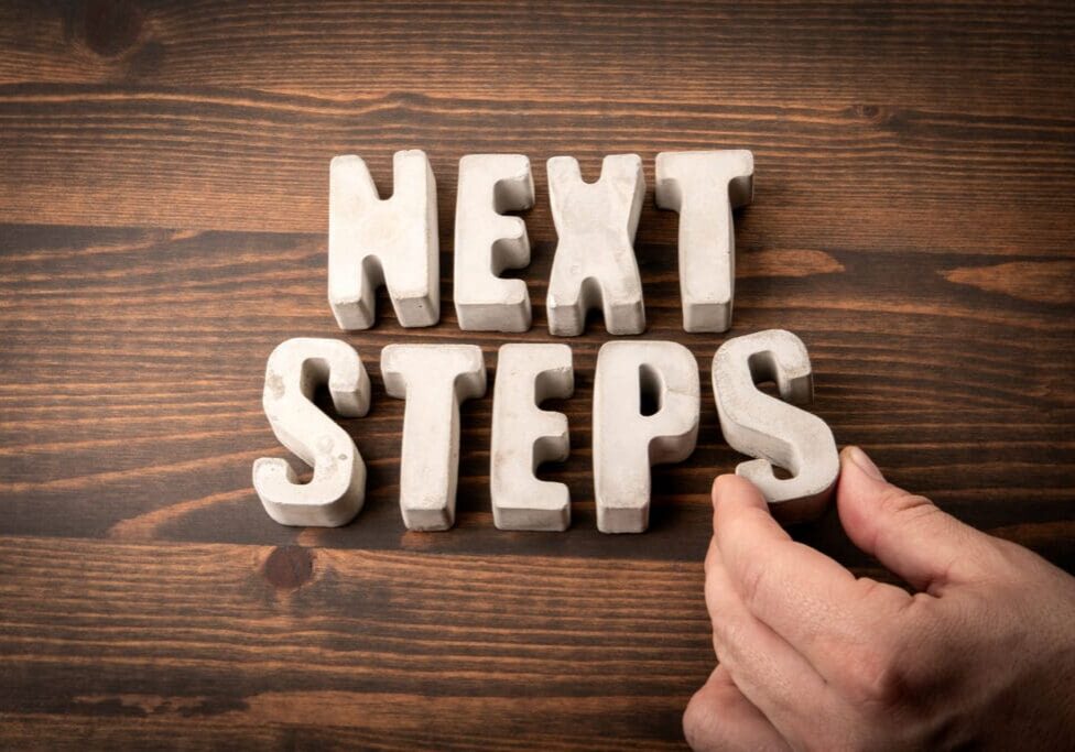 NEXT STEPS. Concrete alphabet letters on a wooden texture background Career transitions is hard but needed next step.