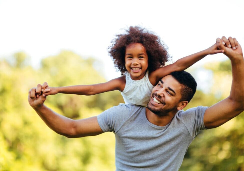 Portrait of young father carrying his daughter on his back Father's Day celebrations.