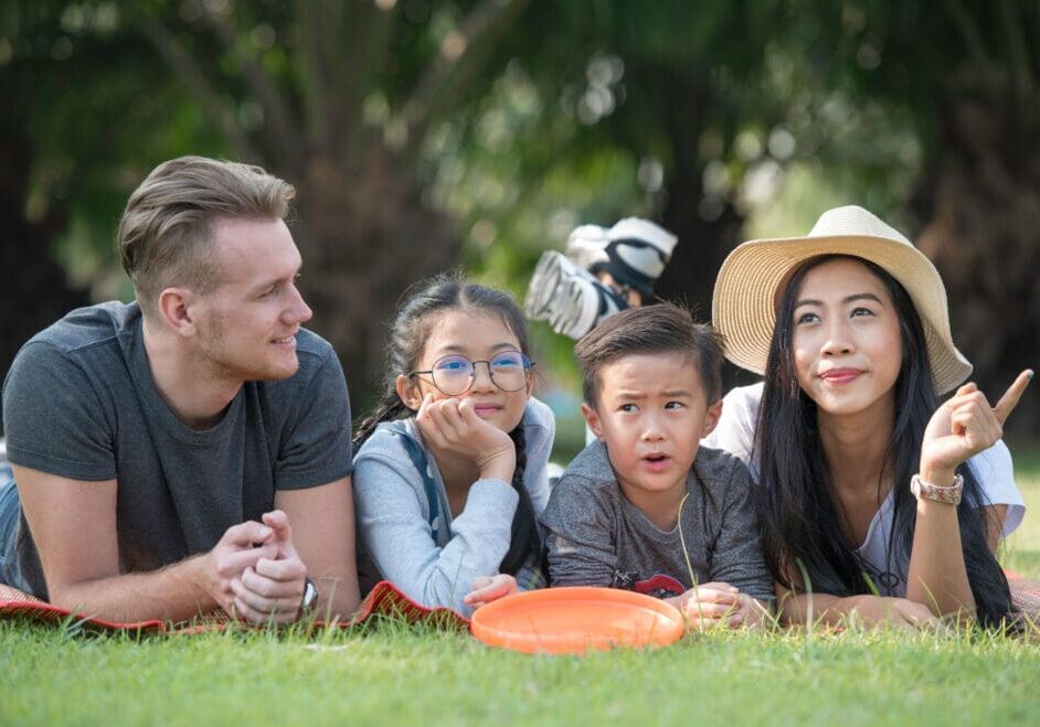Happy family day vacation spend time together, lying on green grass in the park. Family Day spent in the park. Family laying down on grass.