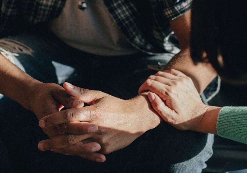 Woman consoling a man Supportive community is shown by a women holding a mans hand.
