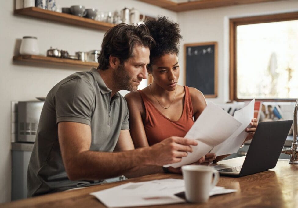 Couple sitting at a table with their laptop, financial planning together.